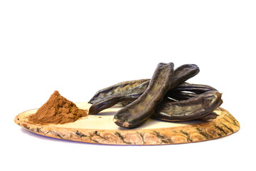 Organic carob pods and carob powder on wood. isolated on white background