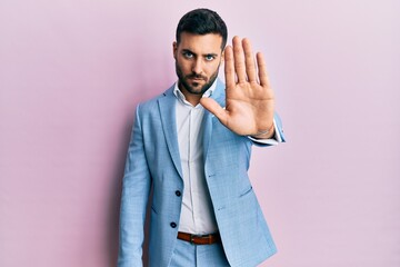 Young hispanic businessman wearing business jacket doing stop sing with palm of the hand. warning...