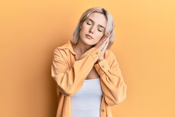 Young blonde girl wearing casual clothes sleeping tired dreaming and posing with hands together while smiling with closed eyes.