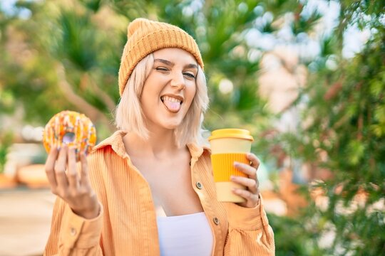 Young blonde girl smiling happy having breakfast at the park.