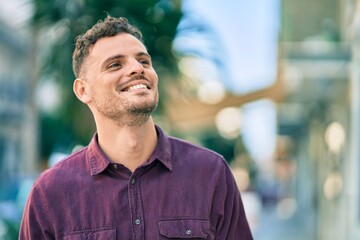 Young hispanic man smiling happy standing at the city.