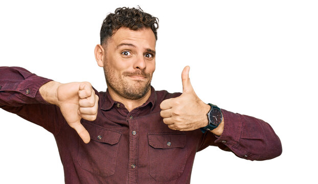 Young hispanic man wearing casual clothes doing thumbs up and down, disagreement and agreement expression. crazy conflict