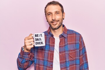 Young handsome man drinking mug of coffe with best dad ever message looking positive and happy standing and smiling with a confident smile showing teeth