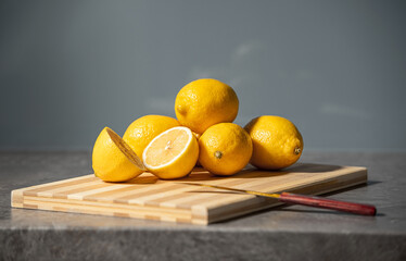 Fresh yellow lemons stacked on stone table top surface of gray marble kitchen background. Citrus...