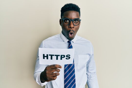 Handsome black man holding https privacy url scared and amazed with open mouth for surprise, disbelief face