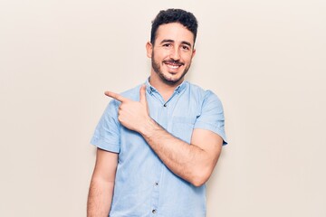 Young hispanic man wearing casual clothes smiling cheerful pointing with hand and finger up to the side