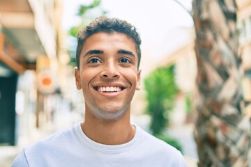 Young latin man smiling happy walking at the city.