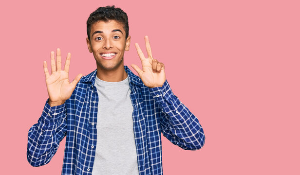 Young handsome african american man wearing casual clothes showing and pointing up with fingers number eight while smiling confident and happy.