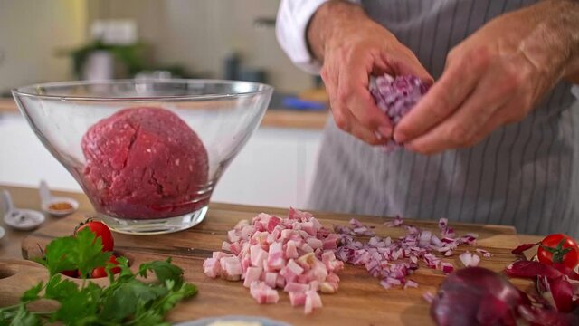 The cook adding the onion in a bowl with the meat.
