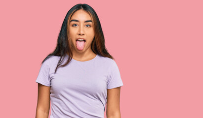 Young latin woman wearing casual clothes sticking tongue out happy with funny expression. emotion concept.