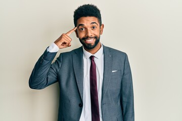 Handsome hispanic man with beard wearing business suit and tie smiling pointing to head with one finger, great idea or thought, good memory