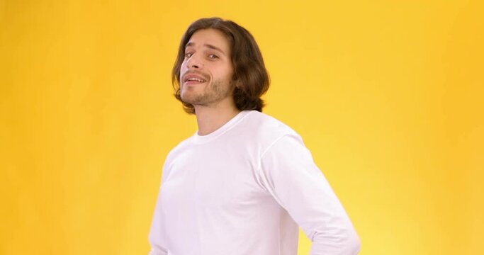 Young confident playful guy pointing finger at camera and winking, choosing you, orange studio background