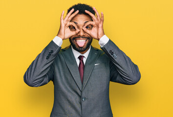 Young african american man wearing business clothes doing ok gesture like binoculars sticking tongue out, eyes looking through fingers. crazy expression.