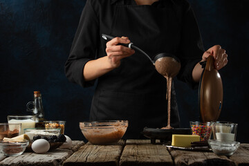 Pastry chef pours dough into waffle making machine.. Backstage of cooking waffle on rustic wooden table with ingredients on dark blue background. Frozen motion. Handmade dessert. Cooking process.