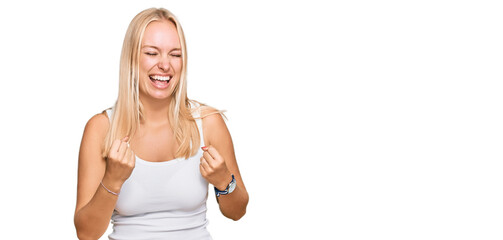 Young blonde girl wearing casual style with sleeveless shirt celebrating surprised and amazed for...