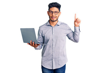 Handsome latin american young man working using computer laptop surprised with an idea or question pointing finger with happy face, number one