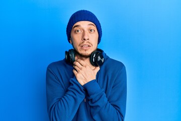 Hispanic young man wearing sweatshirt and headphones shouting and suffocate because painful strangle. health problem. asphyxiate and suicide concept.