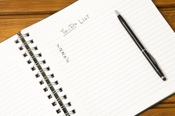 "Wish list" is written on notepad with pen, glasses and calendar on wooden table.