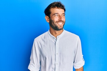 Handsome man with beard wearing elegant shirt looking to side, relax profile pose with natural face and confident smile.