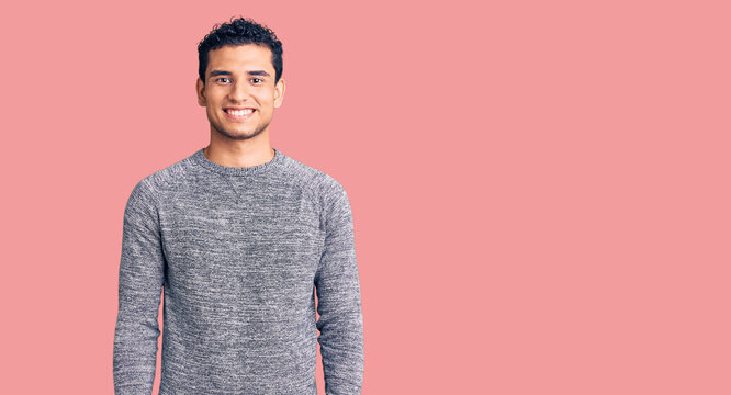 Hispanic handsome young man wearing casual sweater with a happy and cool smile on face. lucky person.