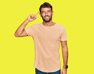 Handsome young man with beard wearing casual tshirt smiling pointing to head with one finger, great idea or thought, good memory