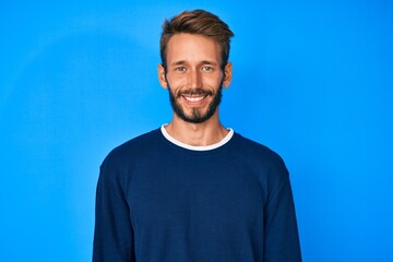 Fototapeta premium Handsome caucasian man with beard wearing casual sweater looking positive and happy standing and smiling with a confident smile showing teeth