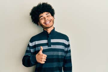 Young african american man with afro hair wearing casual clothes doing happy thumbs up gesture with hand. approving expression looking at the camera showing success.