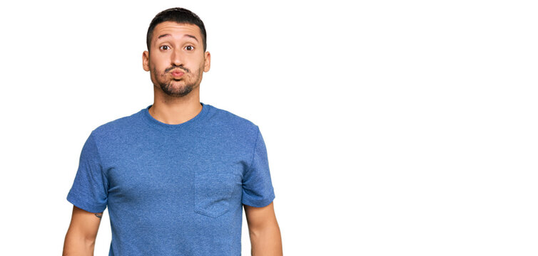 Handsome man with tattoos wearing casual clothes puffing cheeks with funny face. mouth inflated with air, crazy expression.