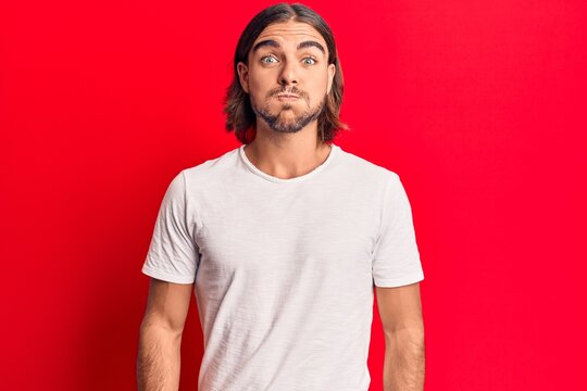 Young handsome man wearing casual clothes puffing cheeks with funny face. mouth inflated with air, crazy expression.