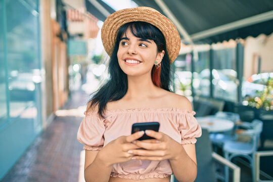 Young hispanic tourist girl wearing summer style using smartphone at the city.