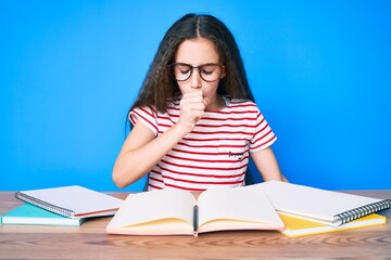 Cute hispanic child girl studying for school exam sitting on the table feeling unwell and coughing as symptom for cold or bronchitis. health care concept.