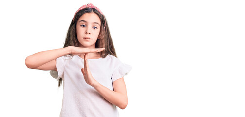 Cute hispanic child girl wearing casual white tshirt doing time out gesture with hands, frustrated...