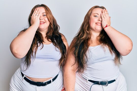 Plus size caucasian sisters woman wearing casual white clothes covering one eye with hand, confident smile on face and surprise emotion.