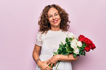 Middle age beautiful woman holding nature bouquet of flowers over isolated pink background looking positive and happy standing and smiling with a confident smile showing teeth