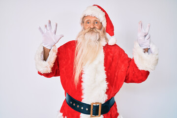 Old senior man with grey hair and long beard wearing santa claus costume with suspenders showing and pointing up with fingers number eight while smiling confident and happy.