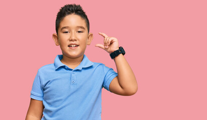 Little boy hispanic kid wearing casual clothes smiling and confident gesturing with hand doing small size sign with fingers looking and the camera. measure concept.