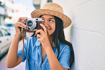 Young latin tourist girl on vacation smiling happy using vintage camera at the city.