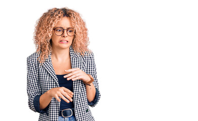 Young blonde woman with curly hair wearing business jacket and glasses disgusted expression, displeased and fearful doing disgust face because aversion reaction.