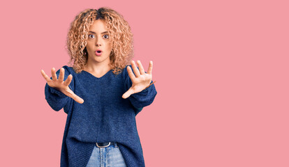 Obraz premium Young blonde woman with curly hair wearing casual winter sweater doing stop gesture with hands palms, angry and frustration expression