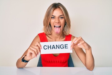 Beautiful caucasian woman holding change banner sticking tongue out happy with funny expression. © Krakenimages.com