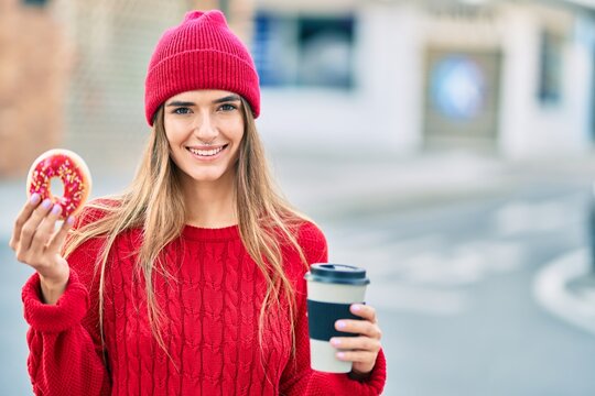 Young hispanic woman wearing wool cap having breakfast at the city.