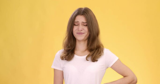 Studio portrait of young woman feeling disgust, appraisingly looking at camera and shaking head in rejection