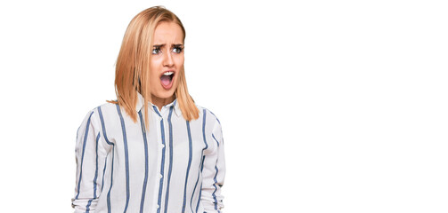 Beautiful caucasian woman wearing casual clothes angry and mad screaming frustrated and furious,...