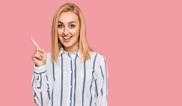 Beautiful caucasian woman wearing casual clothes pointing finger up with successful idea. exited and happy. number one.