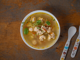 Children's portion of soup with chicken meatballs in a deep white plate