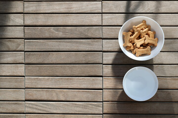 dry dog food and water in bowl on wooden background top view