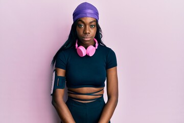 Young african american woman wearing gym clothes and using headphones depressed and worry for distress, crying angry and afraid. sad expression.