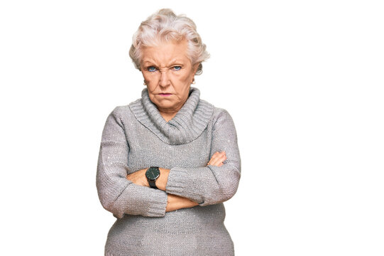 Senior grey-haired woman wearing casual winter sweater skeptic and nervous, disapproving expression on face with crossed arms. negative person.