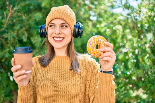 Young blonde woman using headphones and having breakfast at the park.
