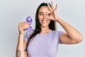 Young hispanic woman holding purple ribbon awareness smiling happy doing ok sign with hand on eye...